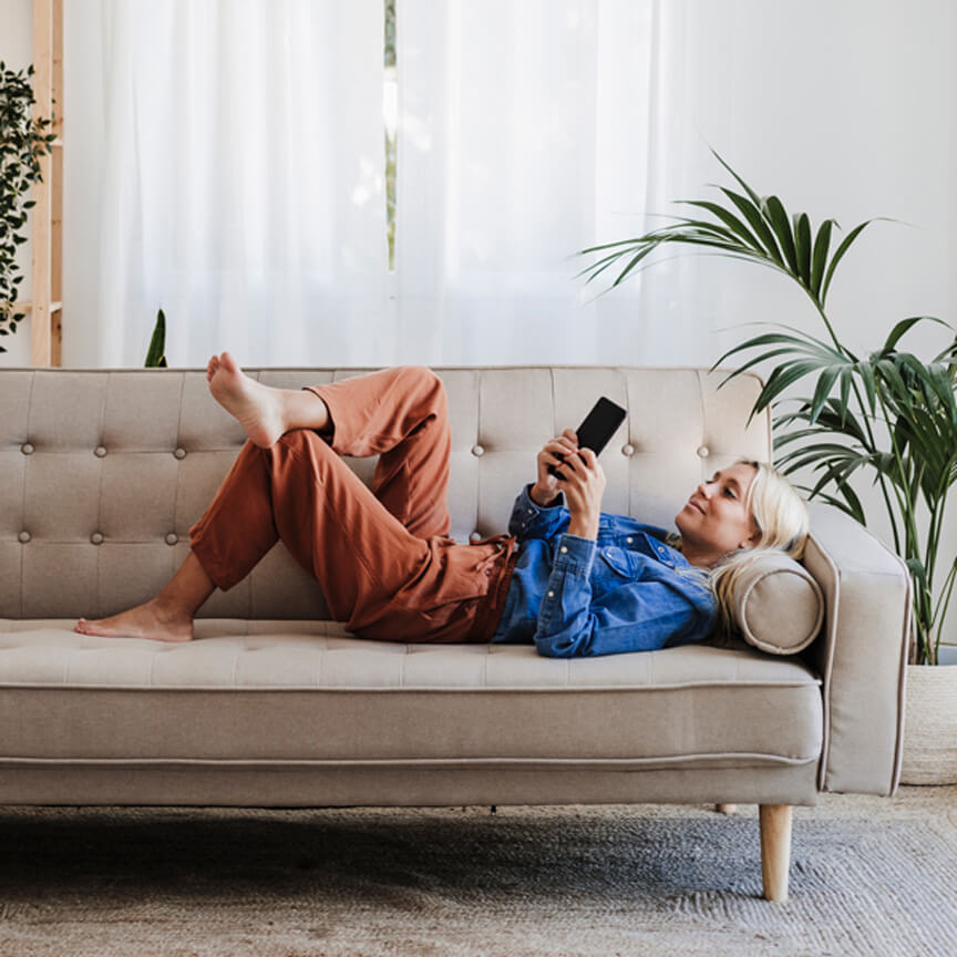 woman laying on a couch looking at her phone